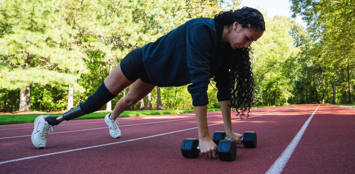 Paralympic adaptive athlete Beatriz Hatz in a plank position holding Nike Dumbbells