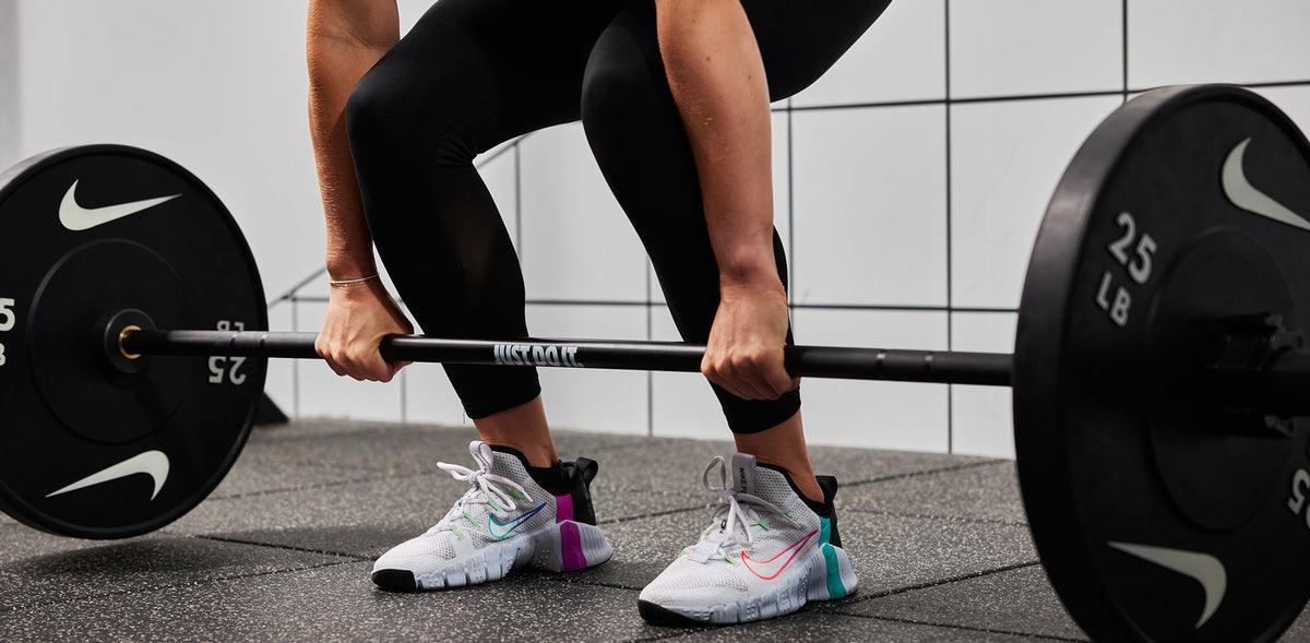 Athlete lifting the Nike coated Premium Barbell 15kg with Nike Rubber Bumper Plates