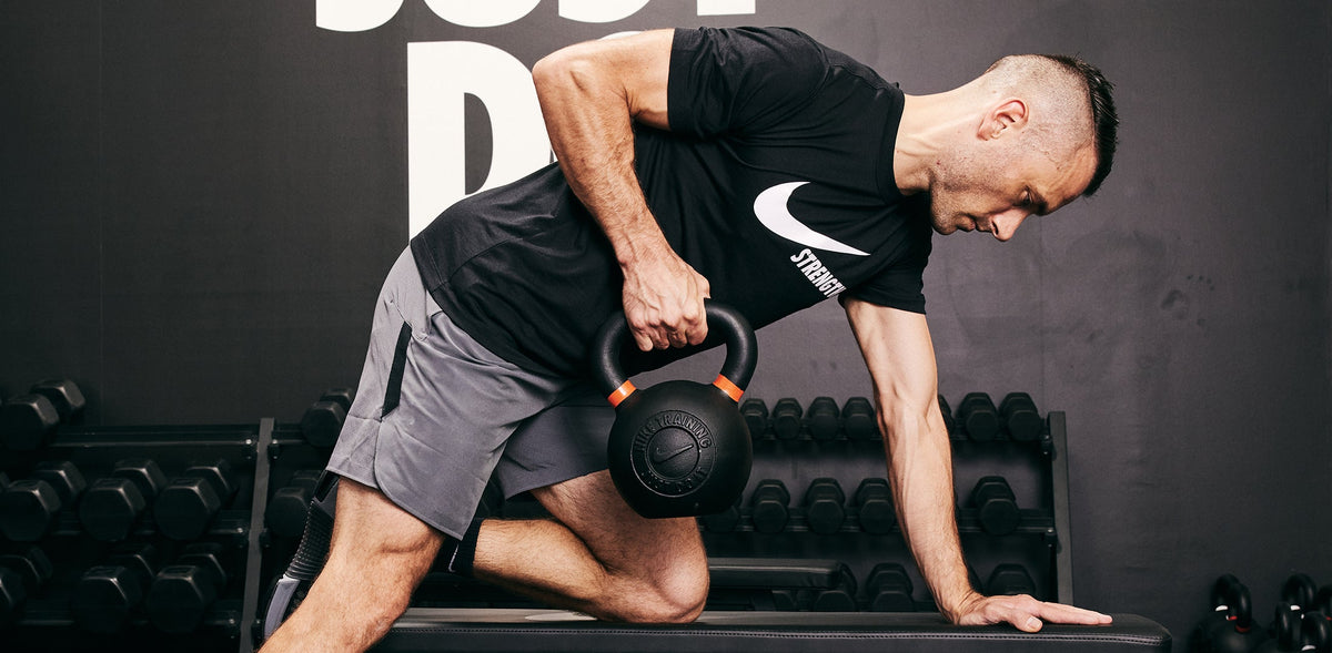 Male athlete rowing the Nike Kettlebell using the Nike Roller Bench