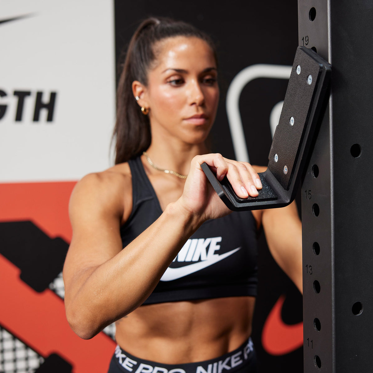 Athlete attaching J-Cups to the Nike Squat Stand