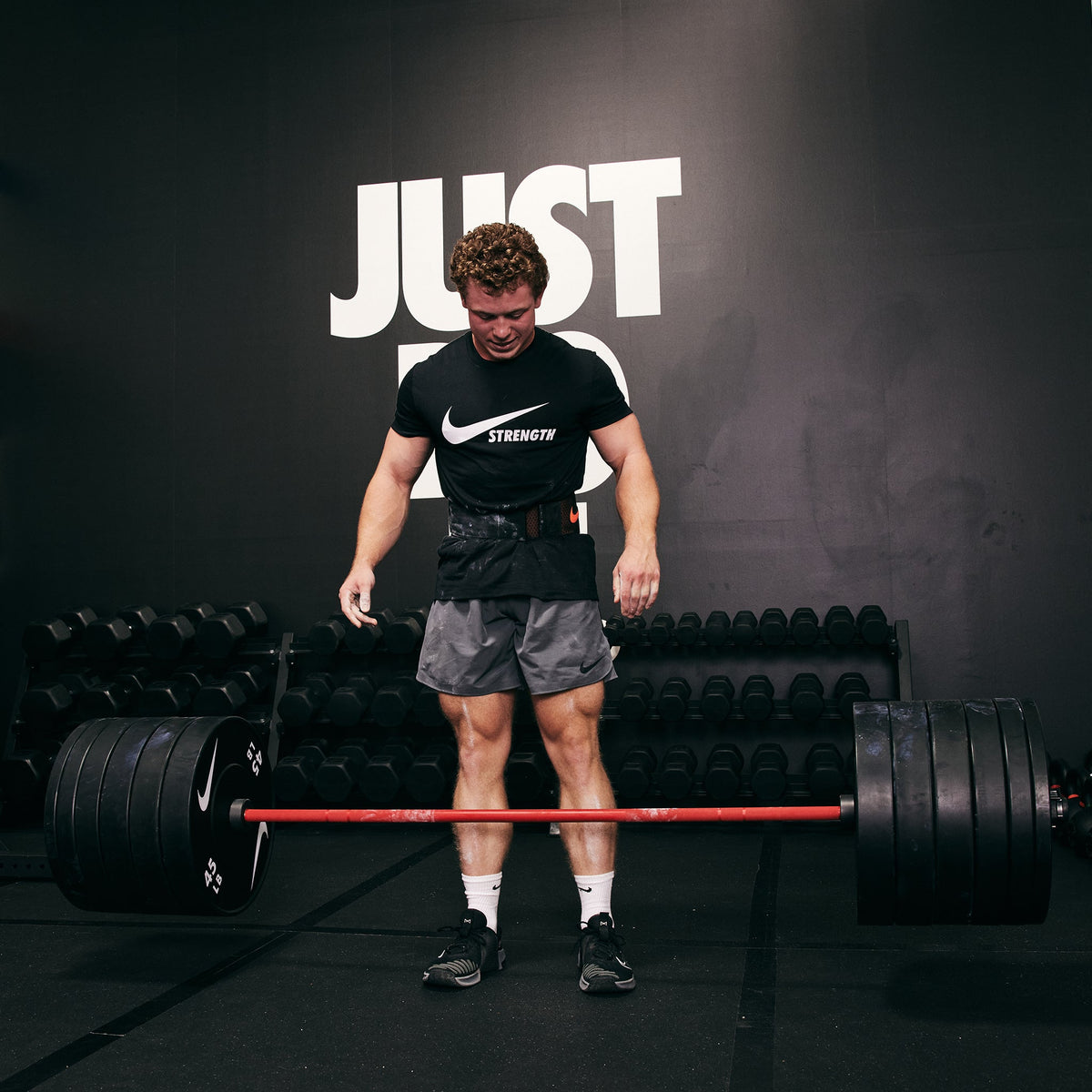 Strong male athlete dropping the Nike Coated Premium Barbell 20kg with Nike Rubber Bumper Plates