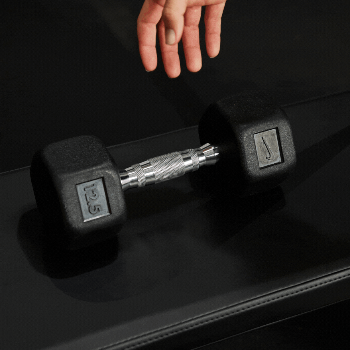 Athlete's hand grabbing the ergonomic handle of the Nike Dumbbell