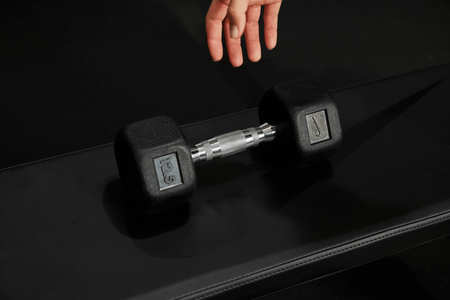 Athlete's hand grabbing the ergonomic handle of the Nike Dumbbell